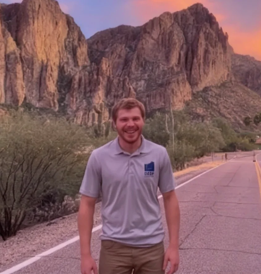 Kye Moffat smiling on a desert road at sunset
