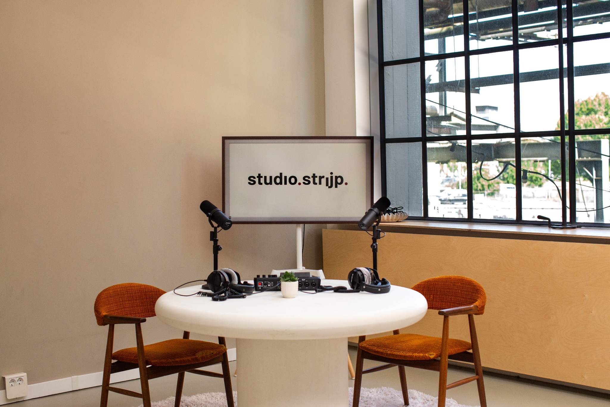 Studio.Strijp — podcasttafel met microfoons en scherm