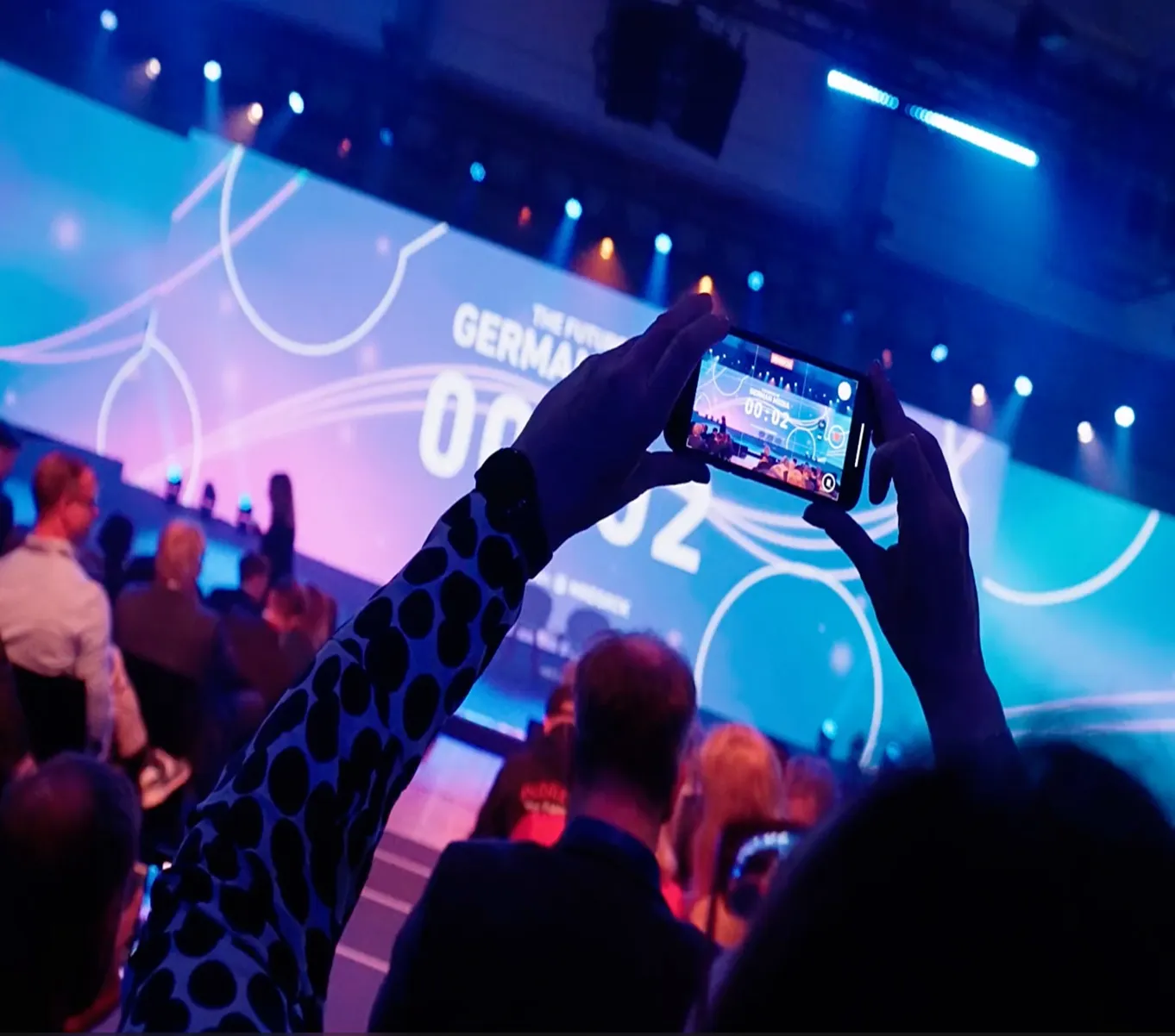 Publikum filmt die Bühne des Summits The Future of German Media mit dem Smartphone