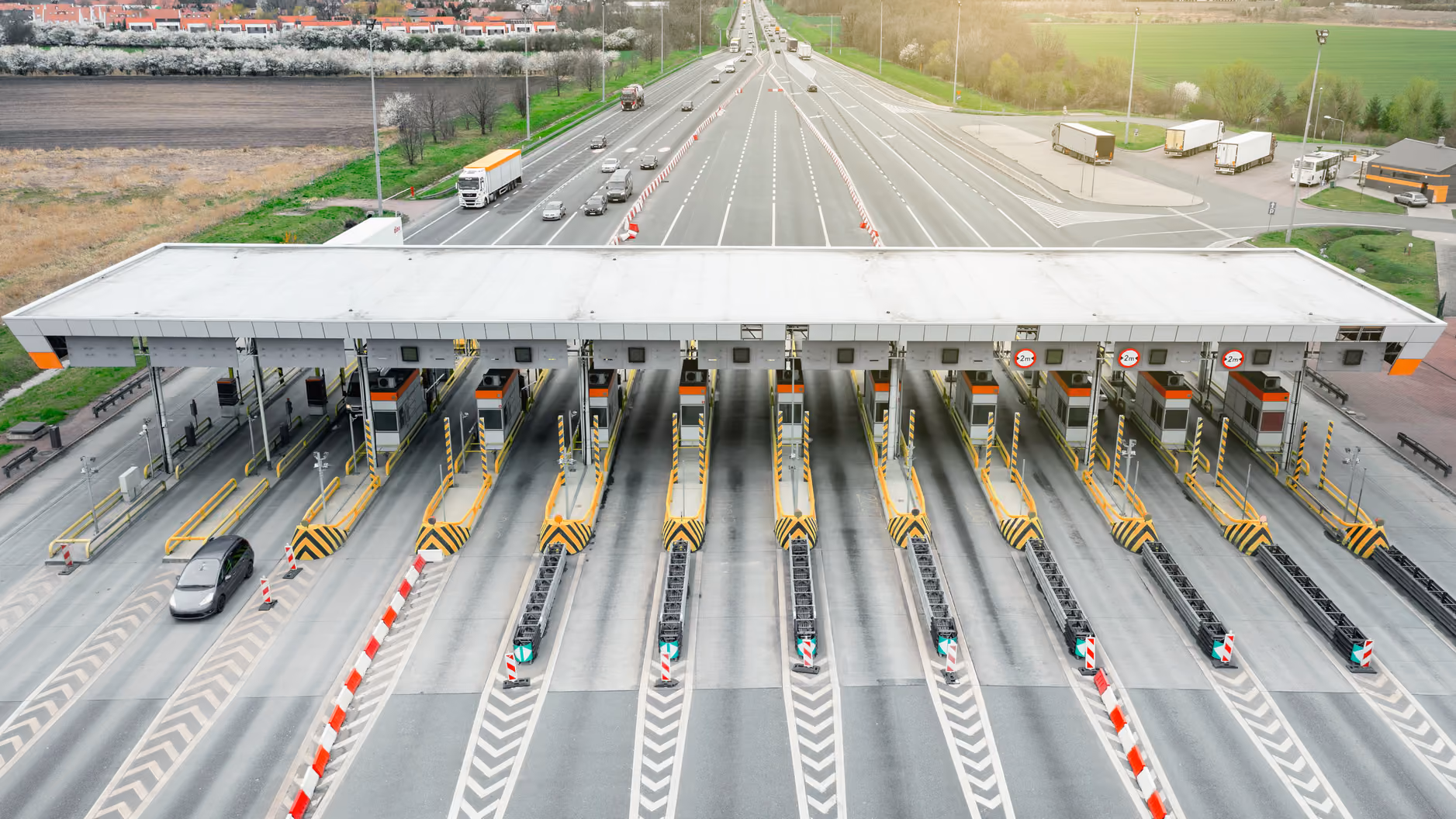 Aerial view of a multi-lane toll plaza with trucks and cars approaching the gates, where GoodVision measures queues and flow per lane