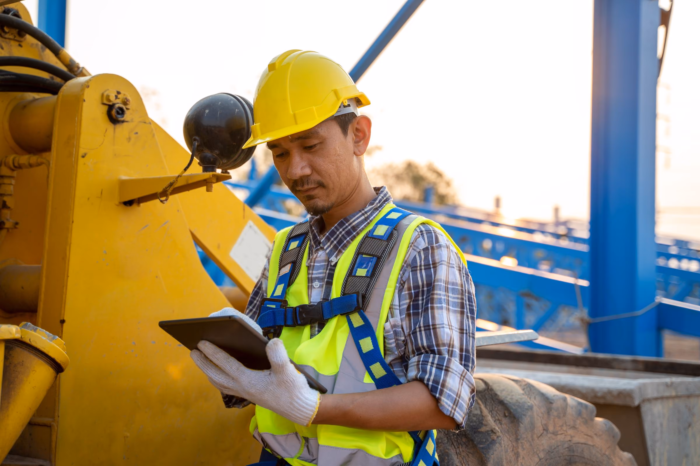 A technician with a tablet checking a loader on site