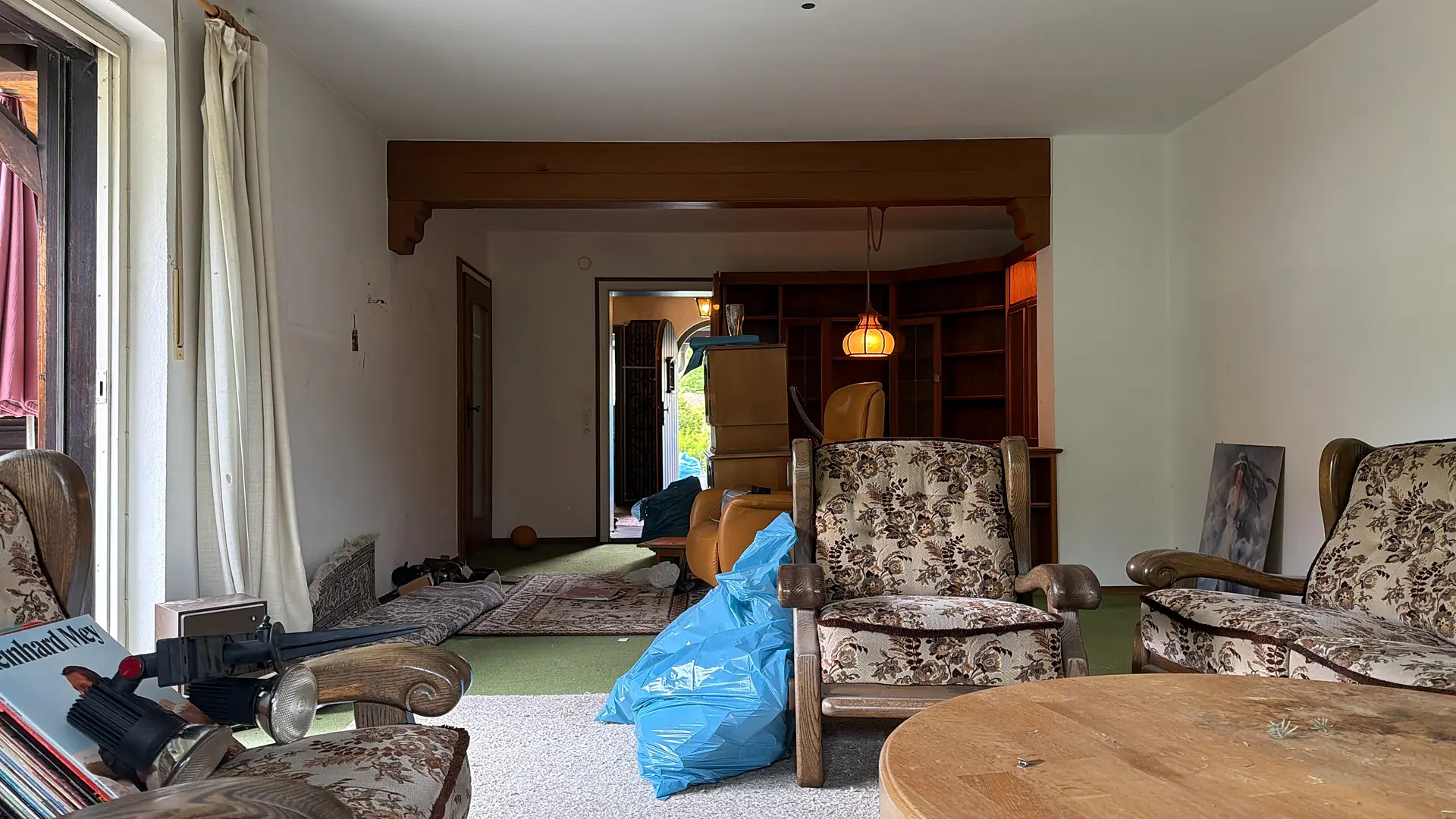 Wohnzimmer bei einer Haushaltsauflösung: alte Sessel, Couchtisch und gepackte Säcke
