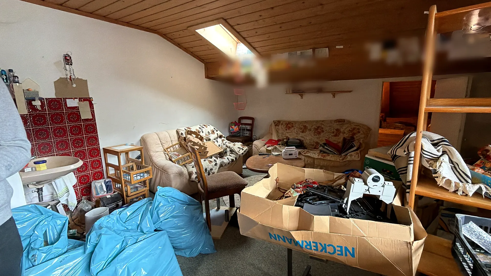 Dachgeschosszimmer mitten in der Entrümpelung: gepackte Säcke, offene Kartons und Möbel