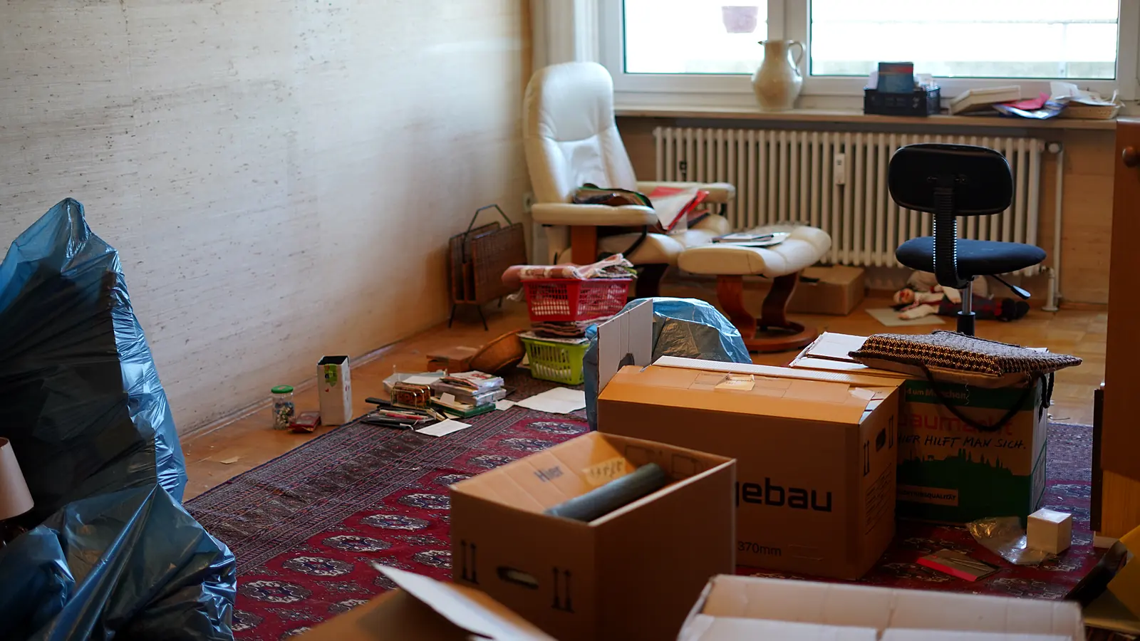 Wohnzimmer mit Umzugskartons auf dem Teppich bei einer Wohnungsauflösung