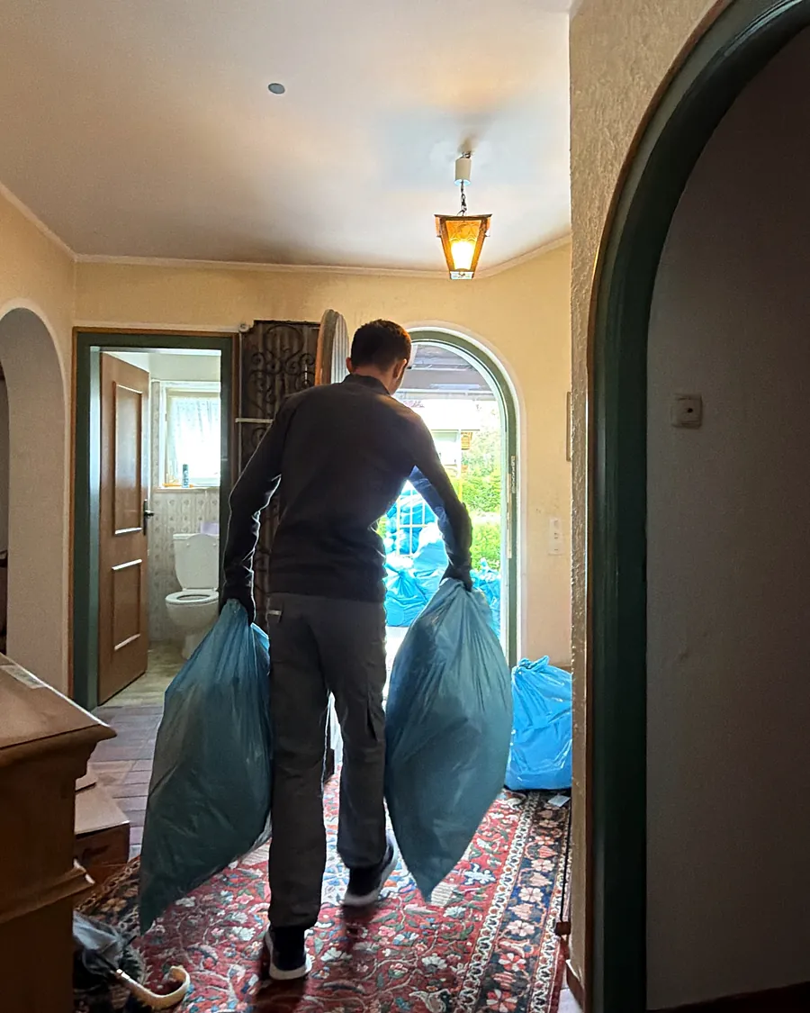 Mitarbeiter trägt gepackte Säcke durch den Hausflur, von hinten