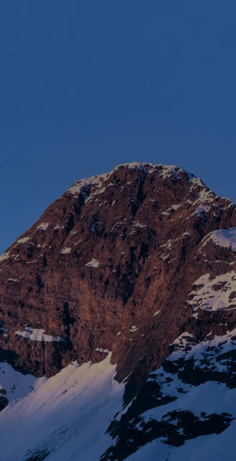 Snowy red mountain peak under a blue sky