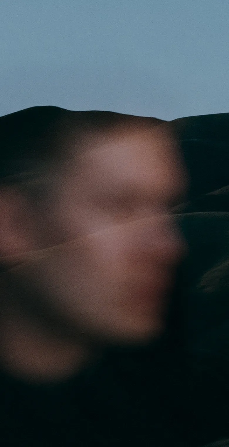 A person reflected in glass over a mountain ridge
