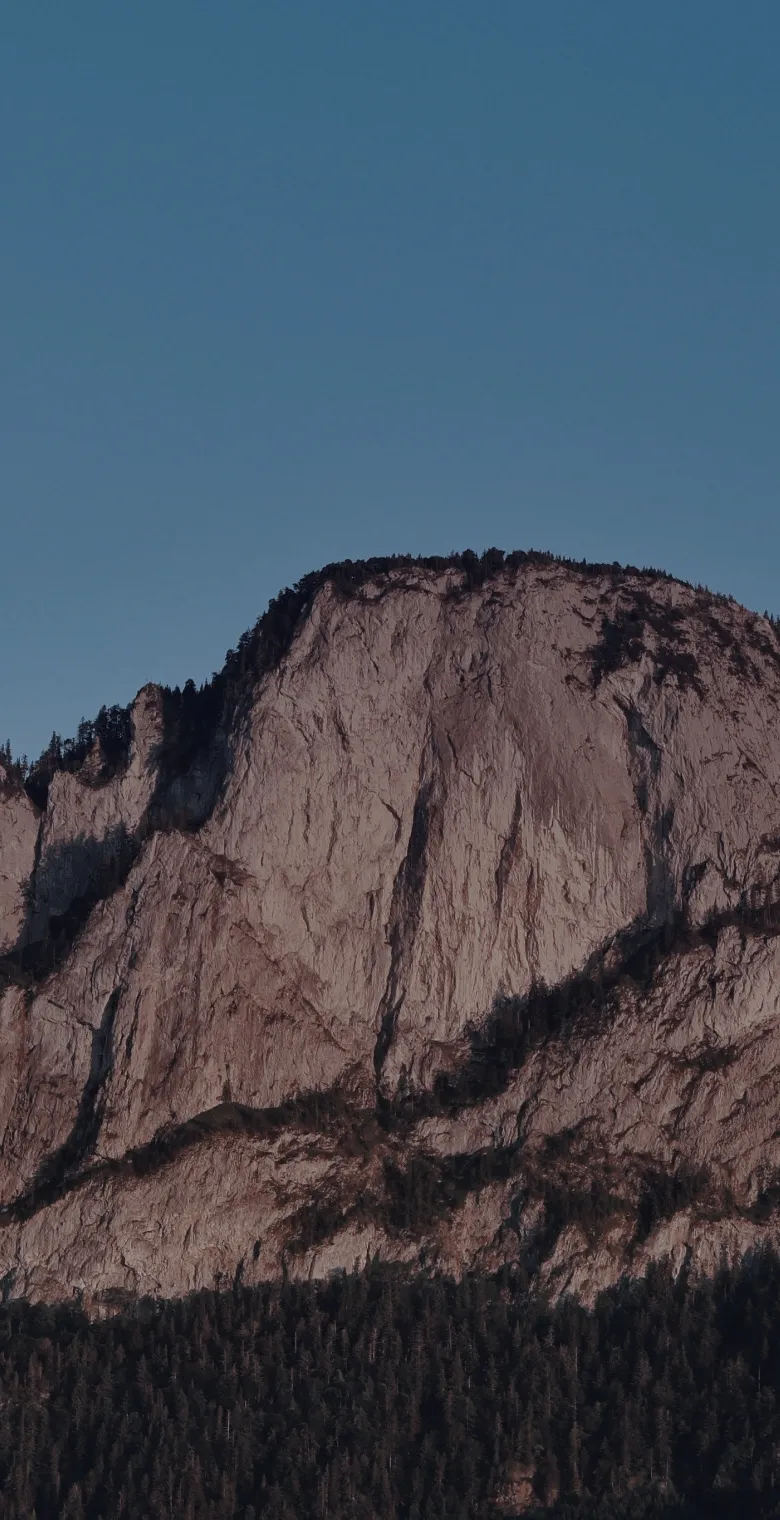 Sheer cliff wall under a teal sky