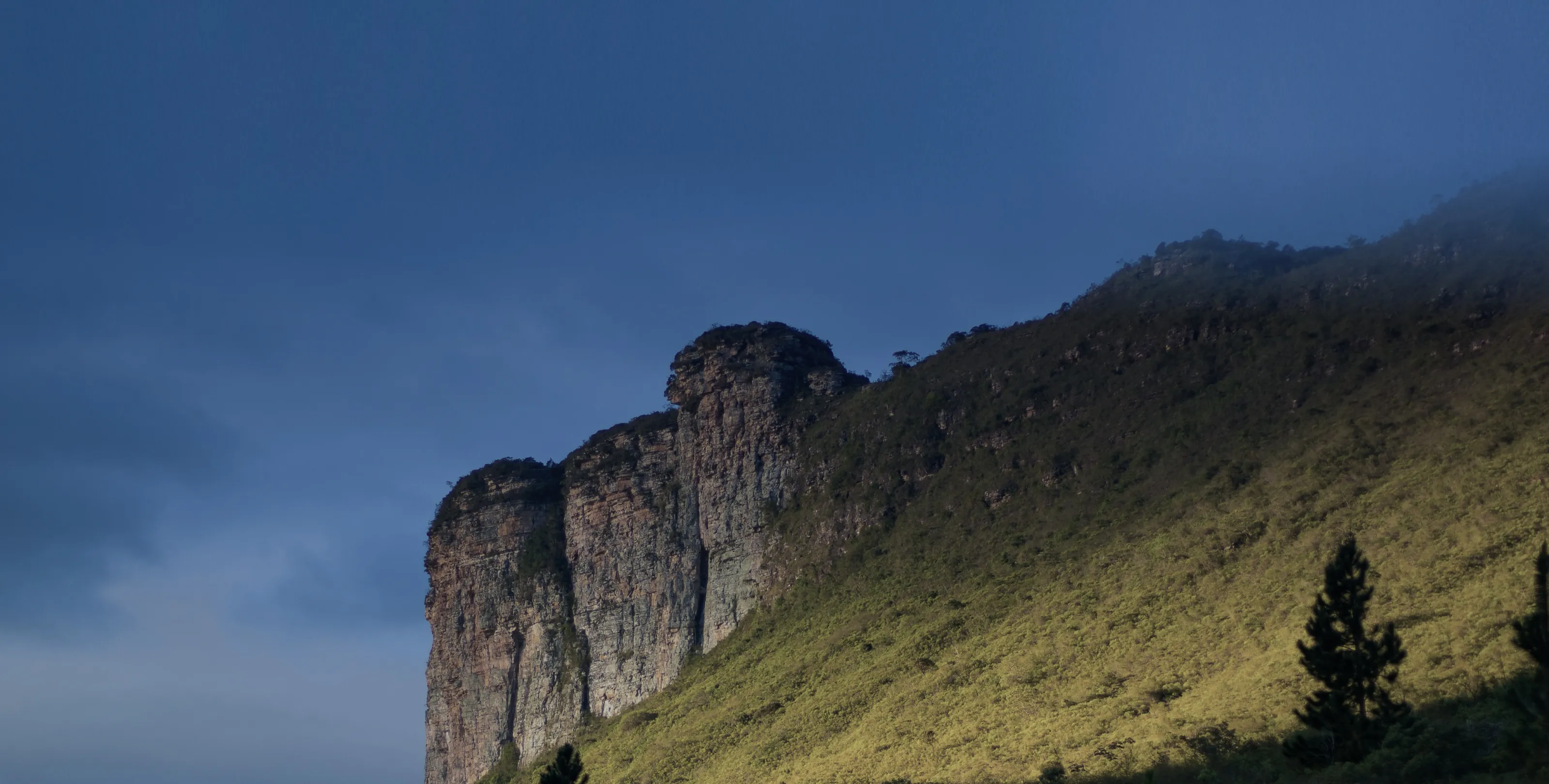 Cliff rising over a green slope