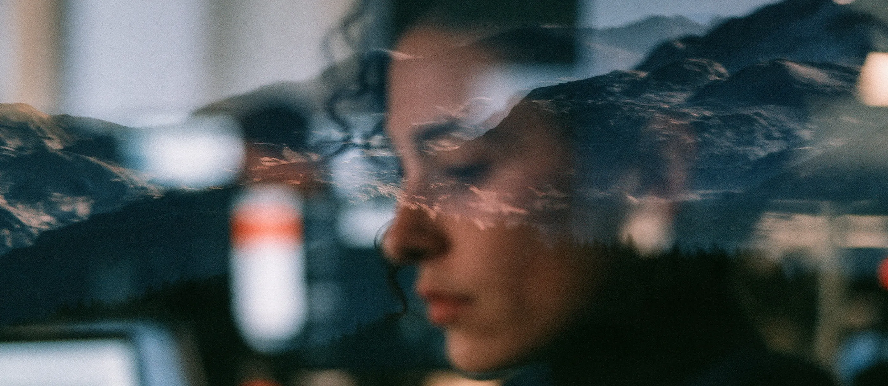 A person at work reflected in glass over a snow-dusted mountain ridge