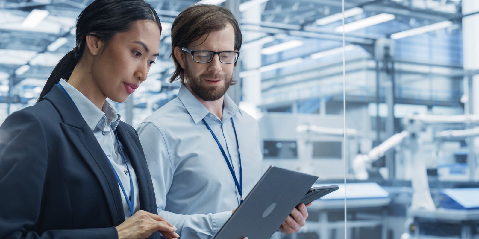 Two colleagues review a tablet in a glass-roofed office.