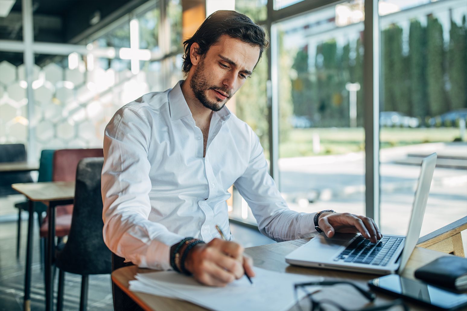 A man works with a laptop and notebook.