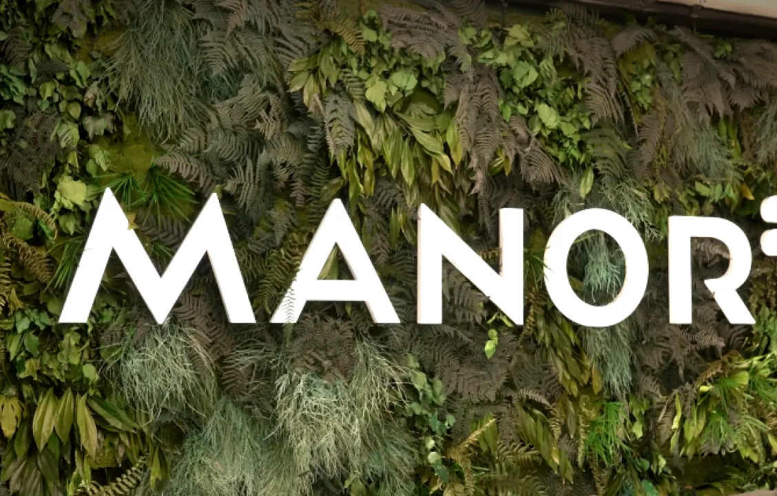 Manor logo on a green plant wall