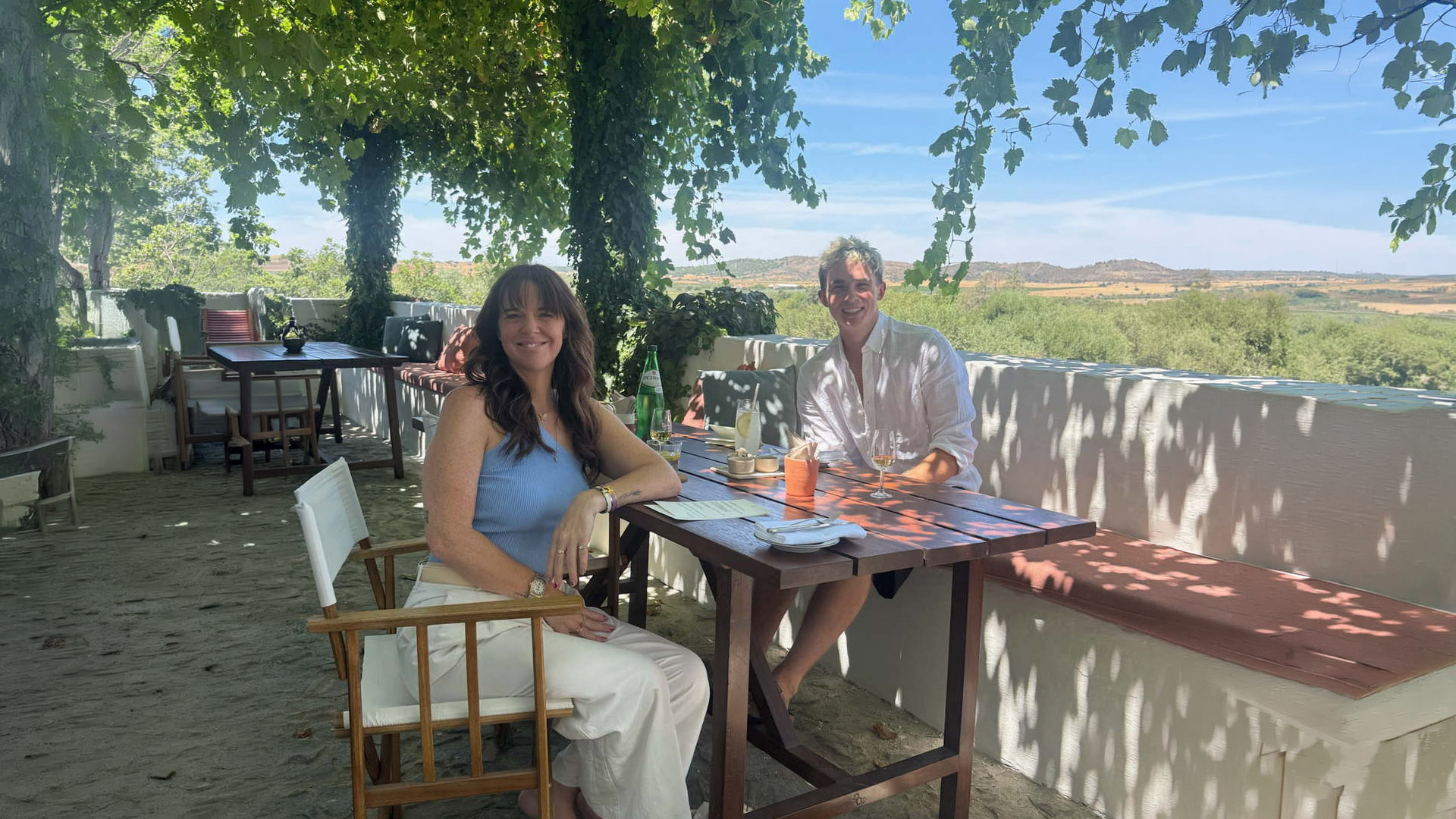 Christine at a table on a shaded garden terrace in Portugal, countryside stretching beyond