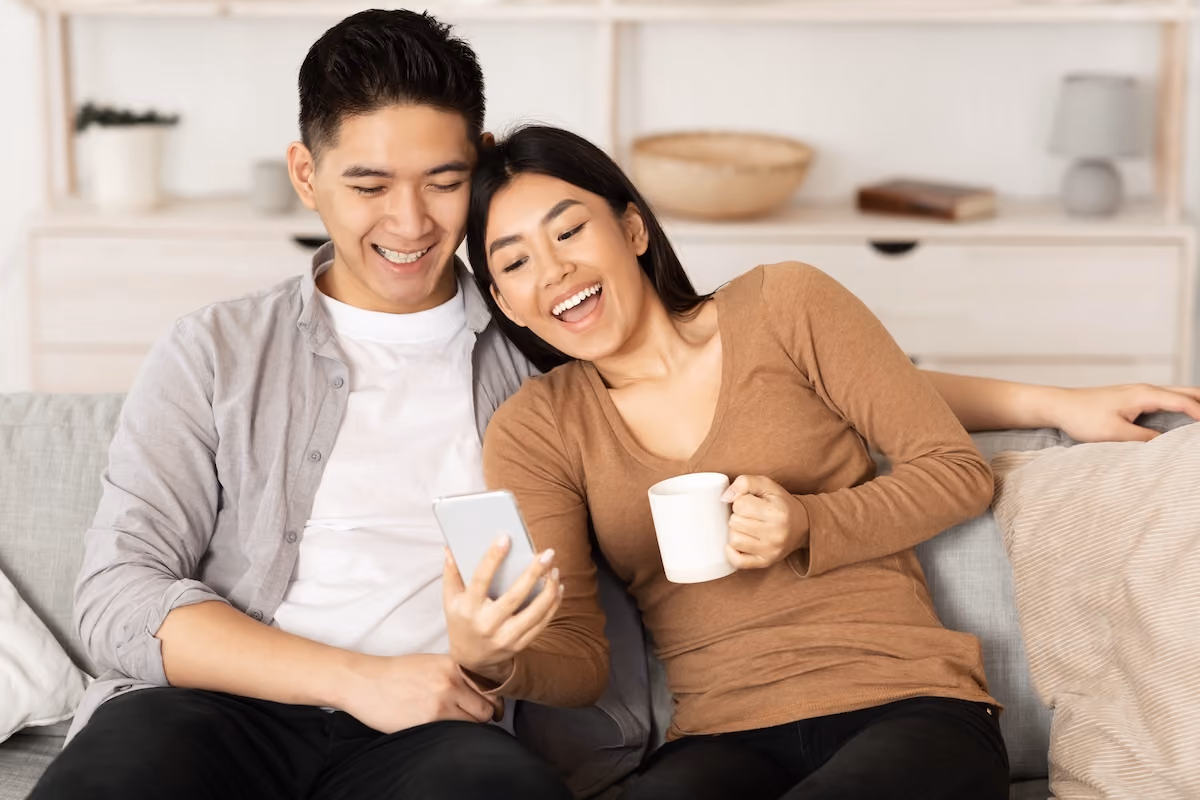 Couple on couch laughing and looking at phone