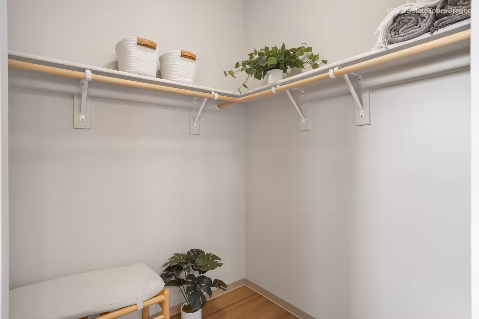 Walk-in closet with white walls, wood flooring, and open shelving.