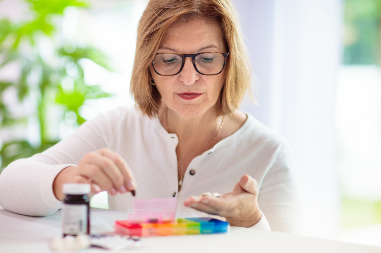 Woman sorting pills into a weekly pill organizer