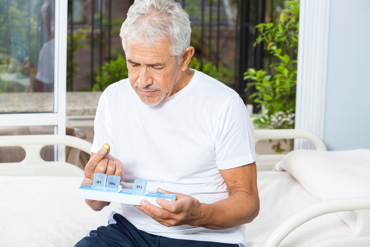 Senior man taking medication from a weekly pill organizer