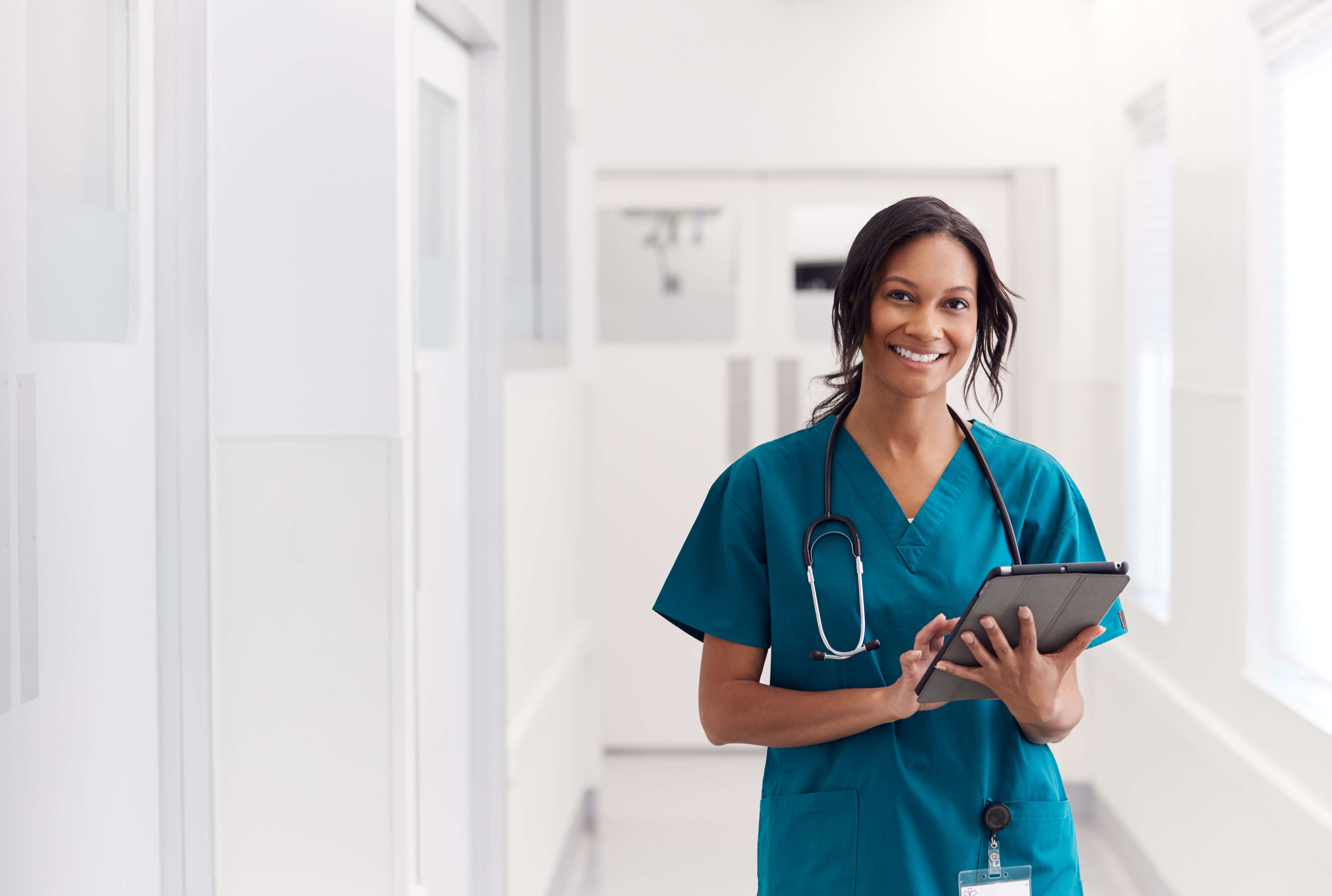 Nurse holding a tablet in a clinic hallway