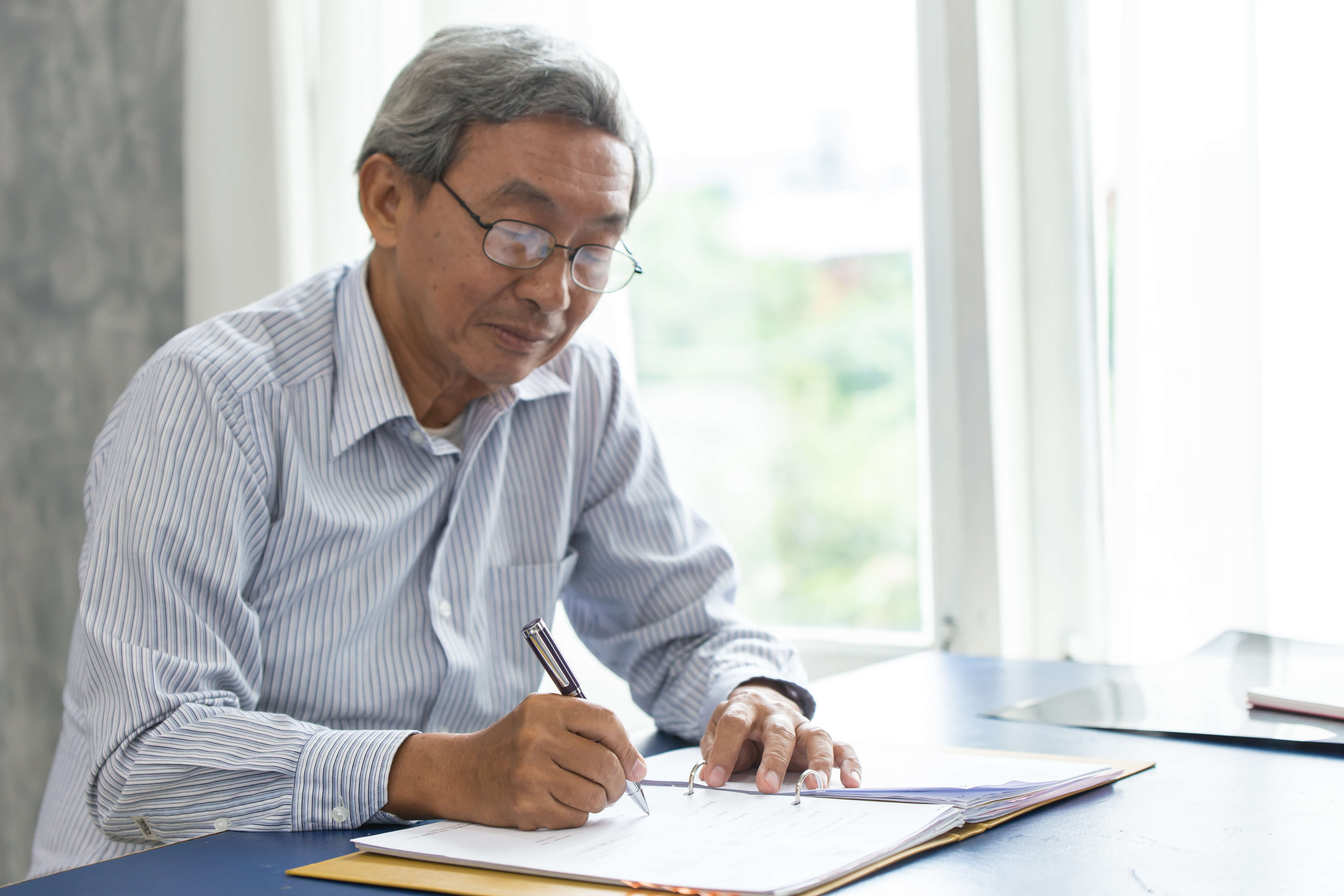 Older man reviewing and signing paperwork