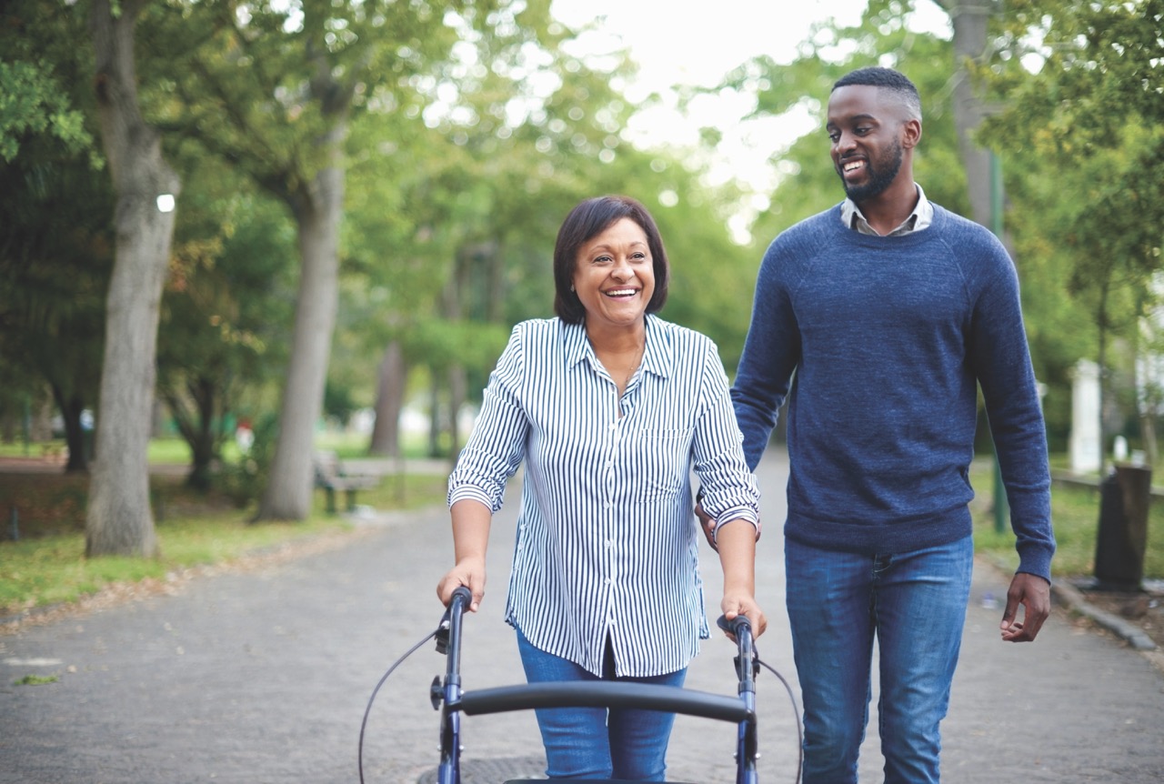 Woman using a walker with support from a family member