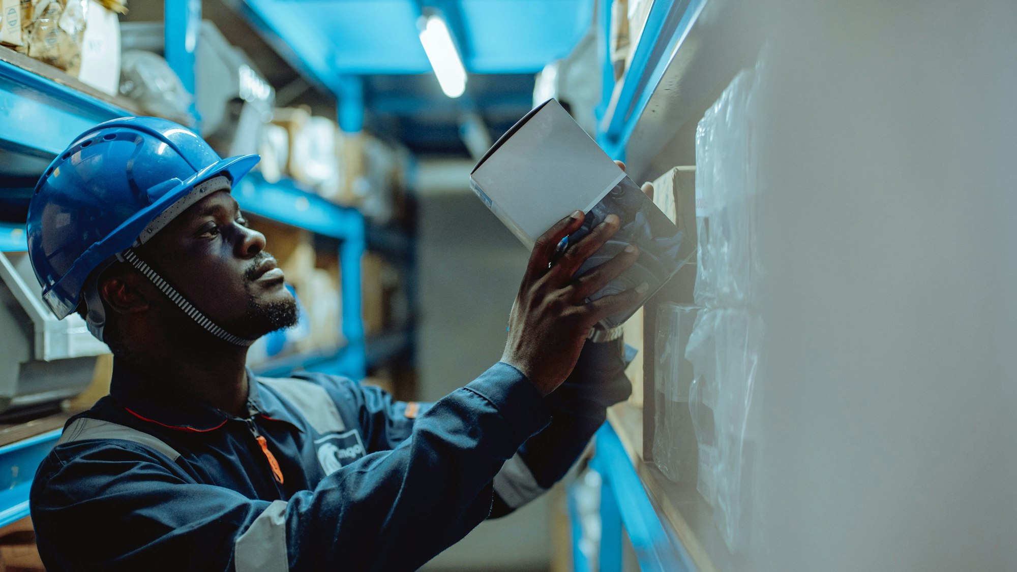 Technician in a hard hat checking equipment in a warehouse