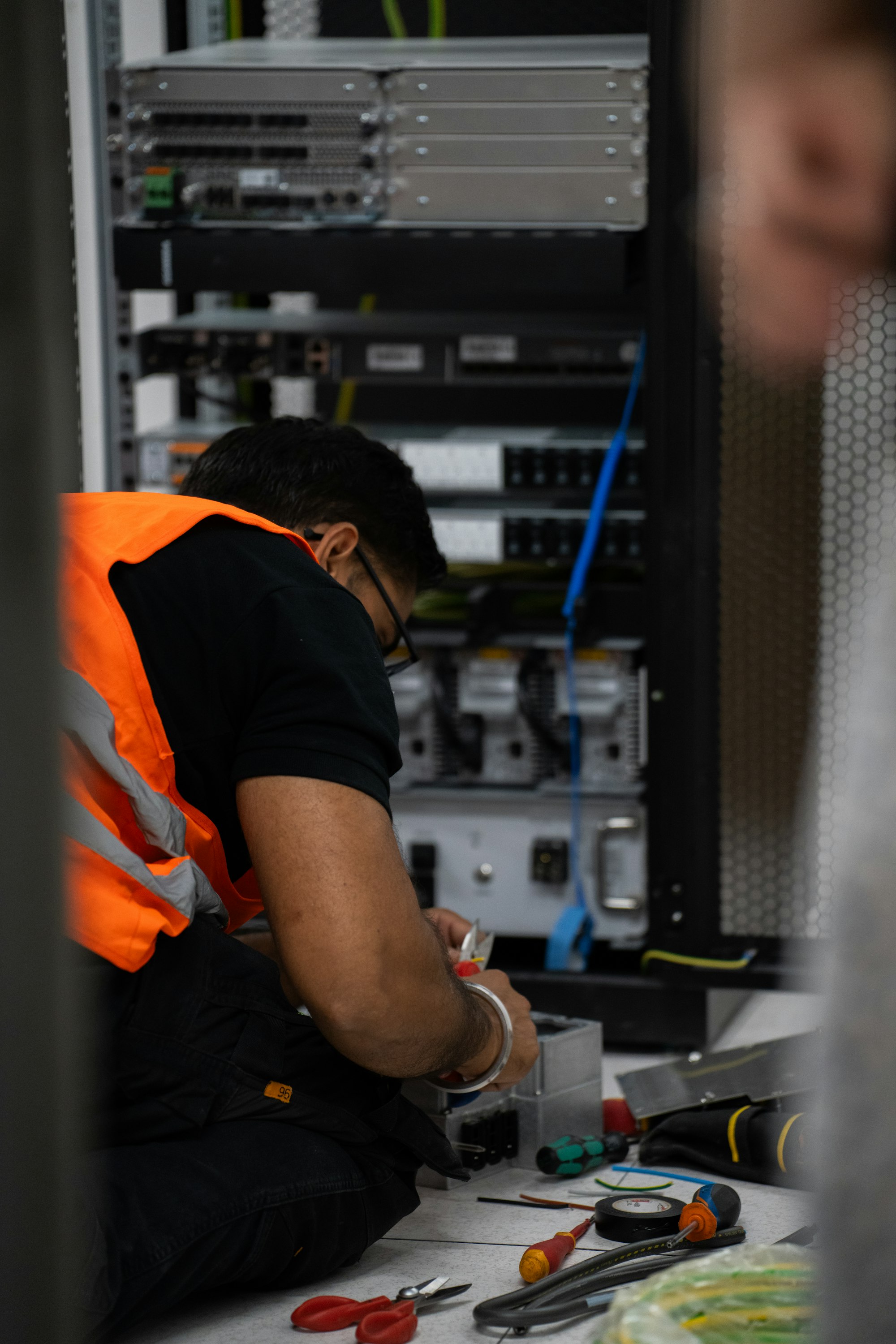 Field technician in a high-visibility vest working on rack equipment