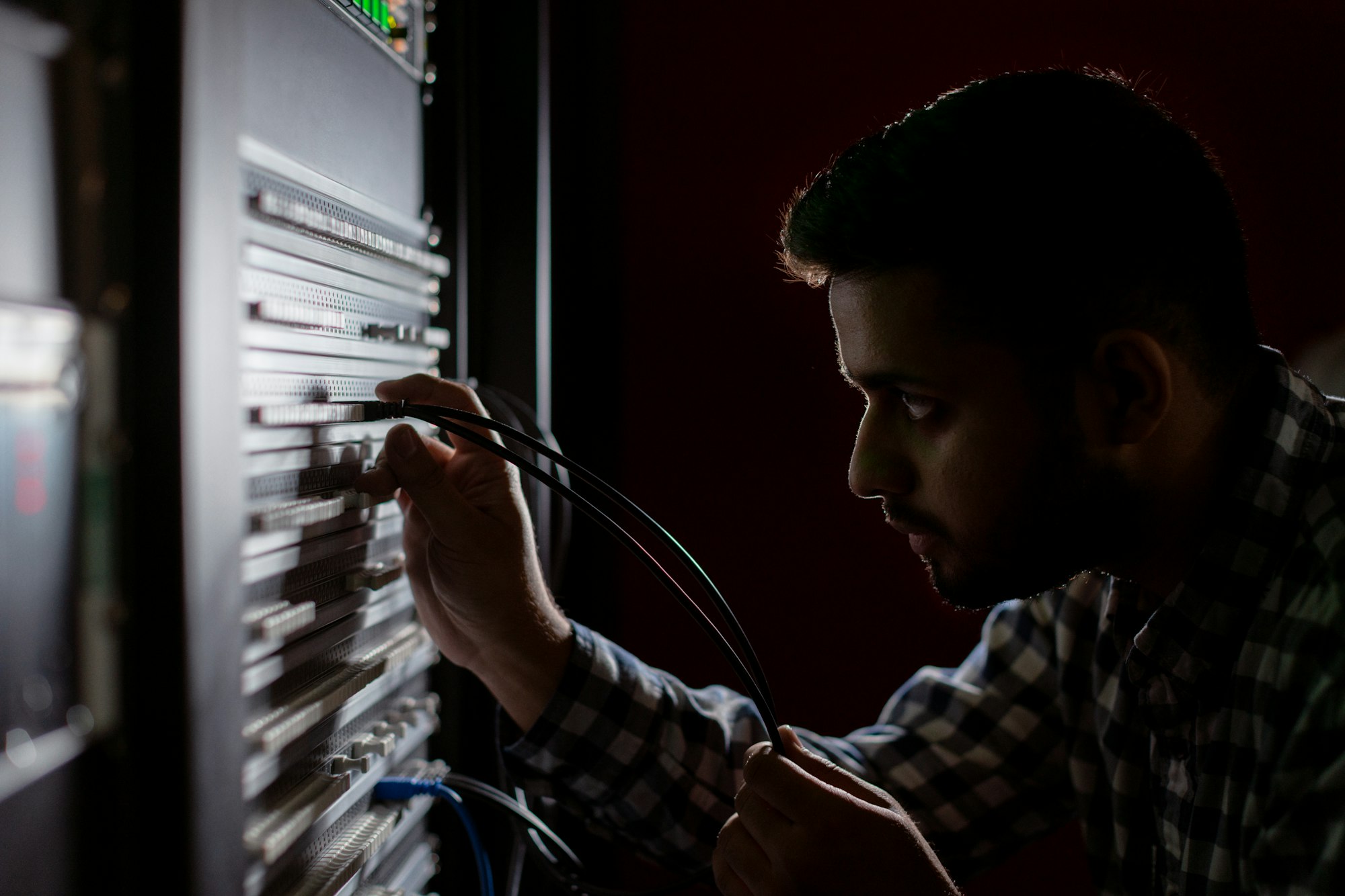 Technician connecting cables at a network patch panel