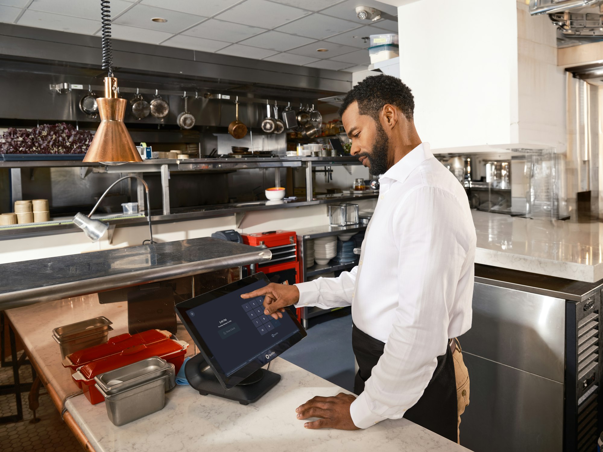Restaurant staff using a touchscreen POS in a commercial kitchen