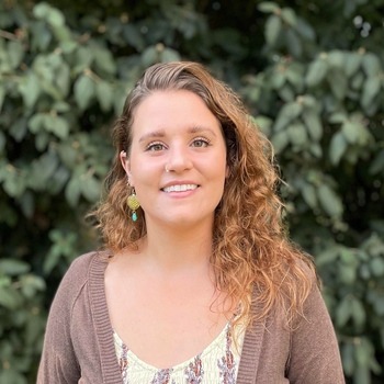 Jessica Birkhimer, MA, LPCC, smiling outdoors in front of green leaves
