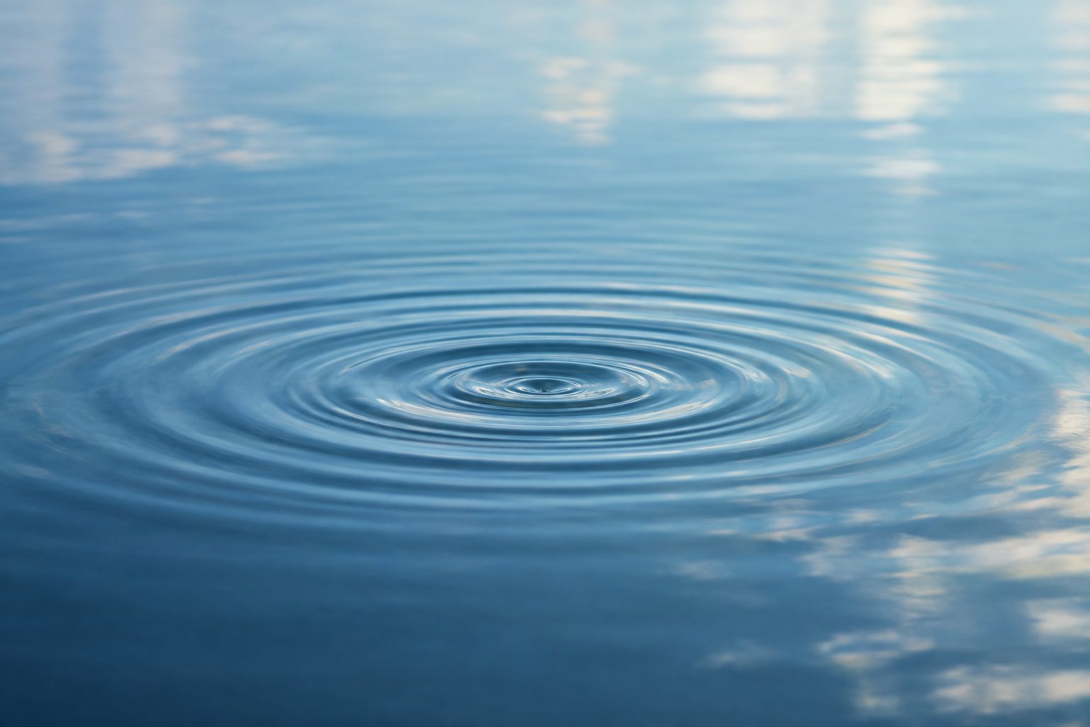 Gentle concentric ripples spreading across still blue water
