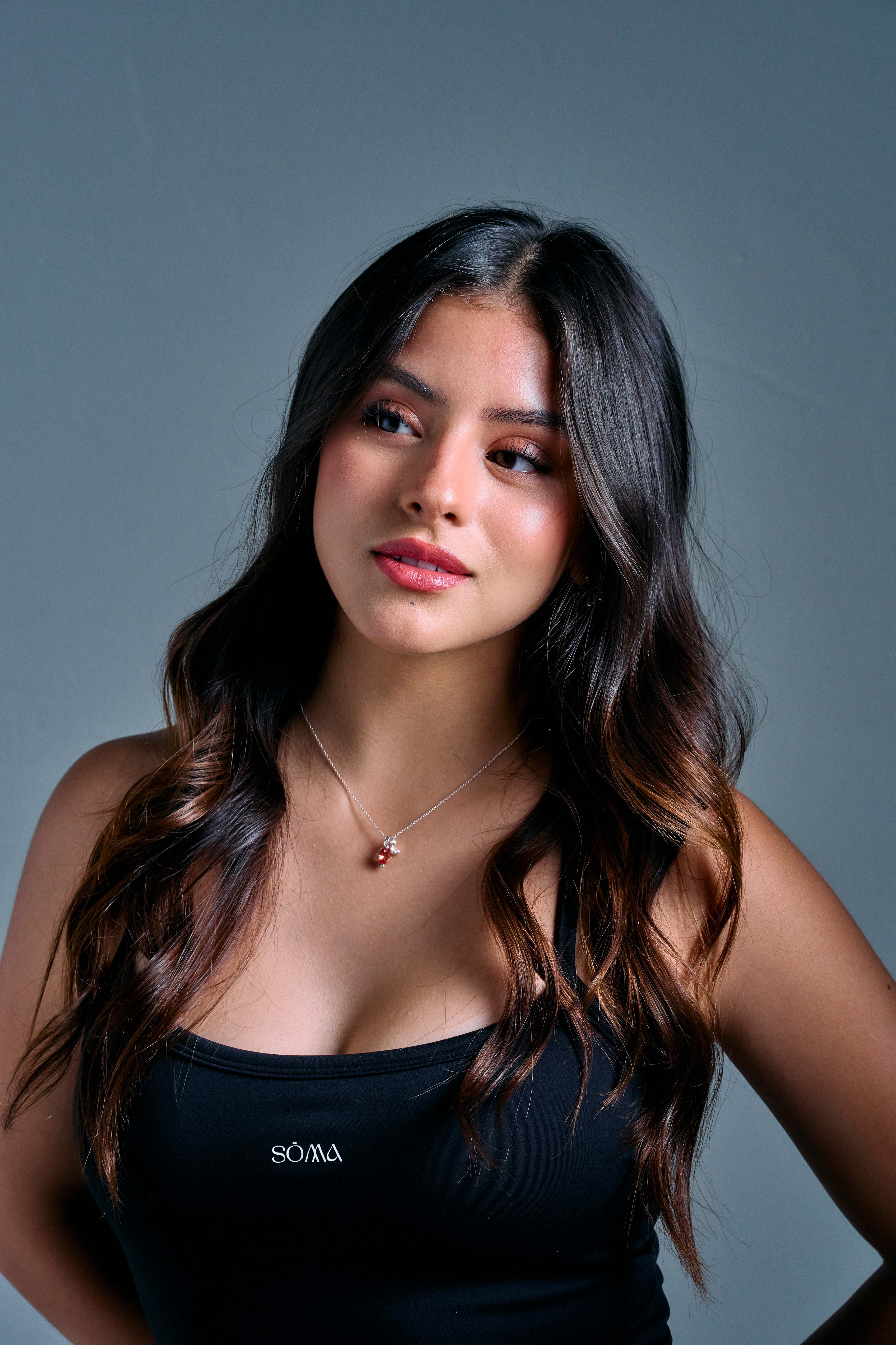 Retrato de estudio de una mujer de cabello largo ondulado sobre fondo gris azulado