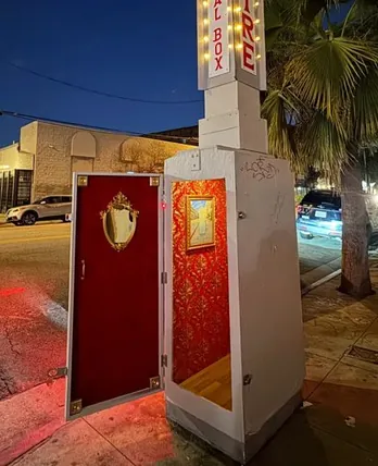 Electrical box on a Los Angeles sidewalk opened at night to reveal a tiny theater with red damask walls and a gilded mirror — by @s.c.mero