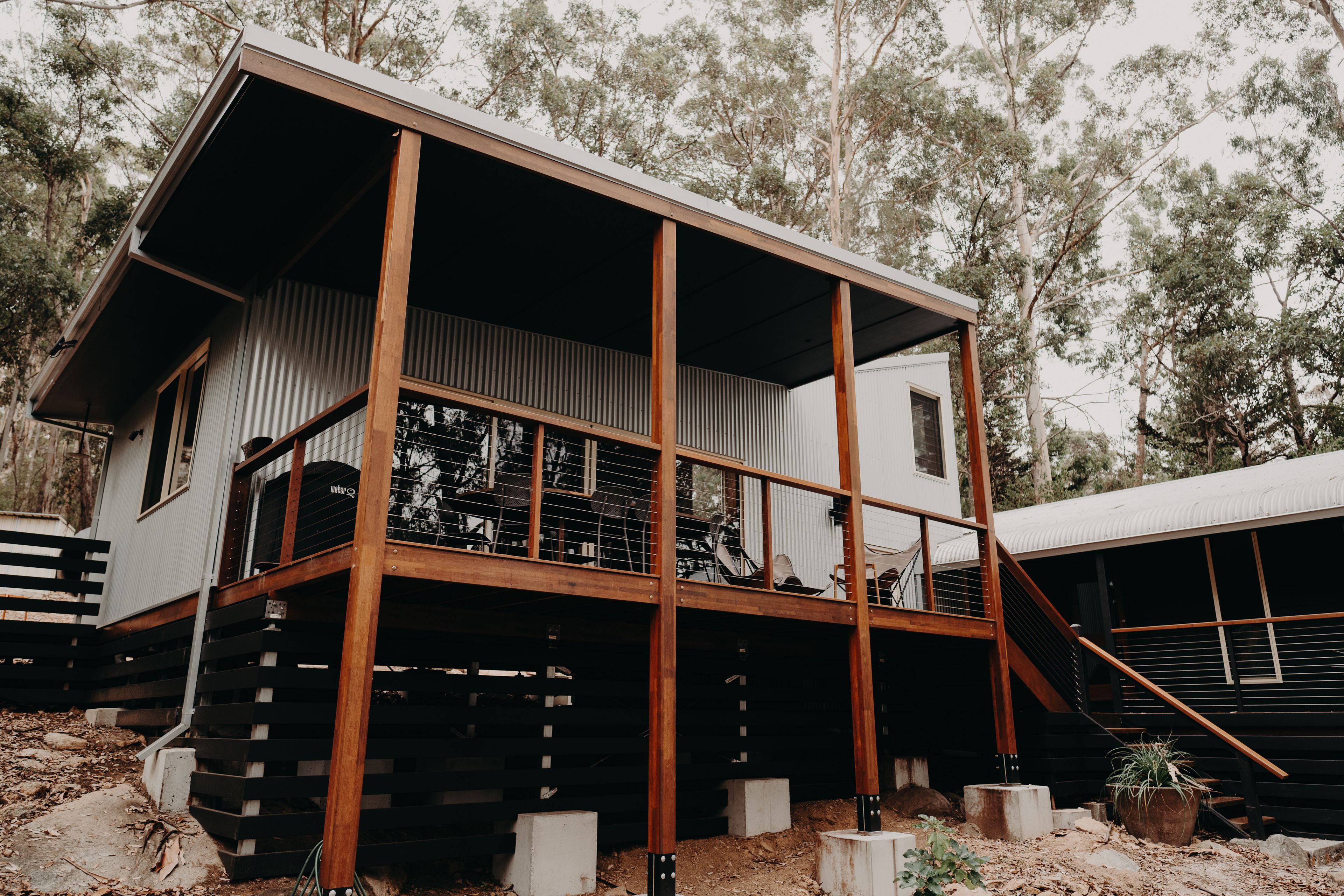 Pavilion raised on timber posts over a sloping bush block