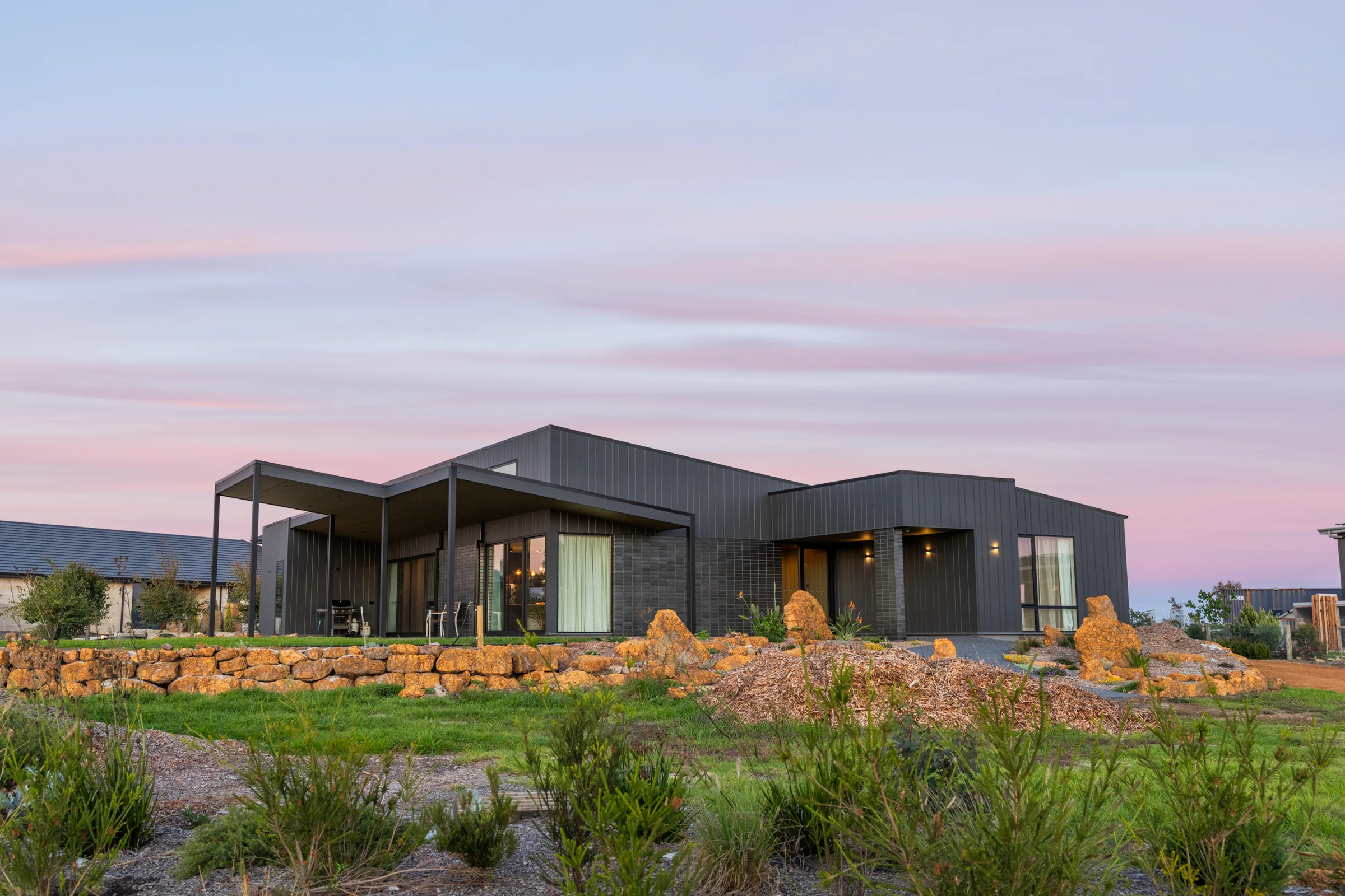 Passive solar home at Springdale Beach Estate, Denmark WA, at dusk across a native garden