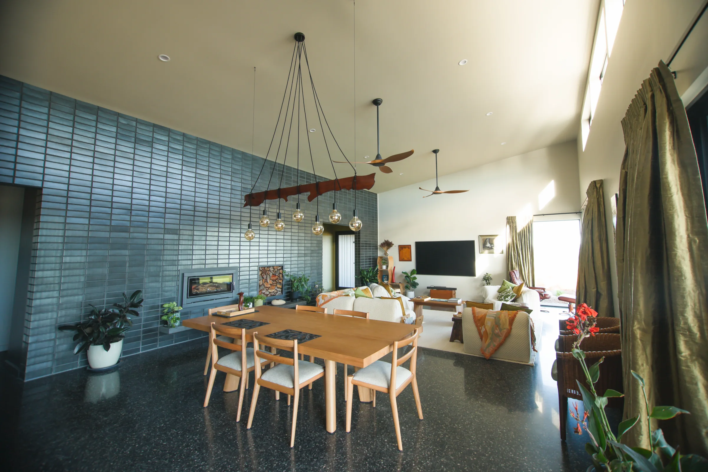 Open-plan living with sun through high windows onto a polished concrete floor