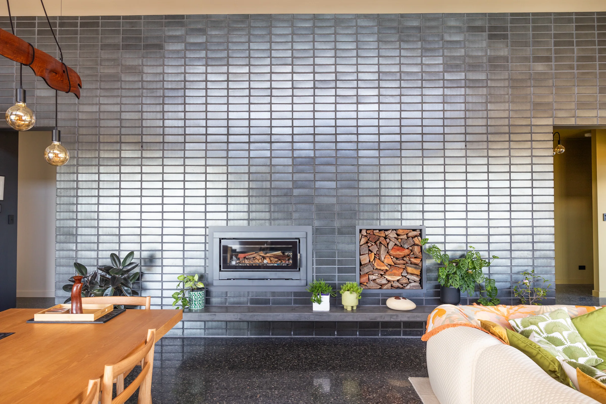 Glazed brick feature wall with wood heater and log niche on a polished concrete floor