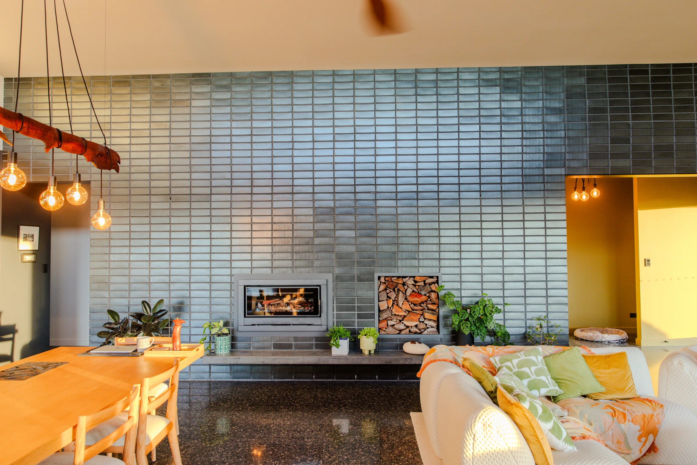 Wood heater lit at golden hour in the glazed brick feature wall