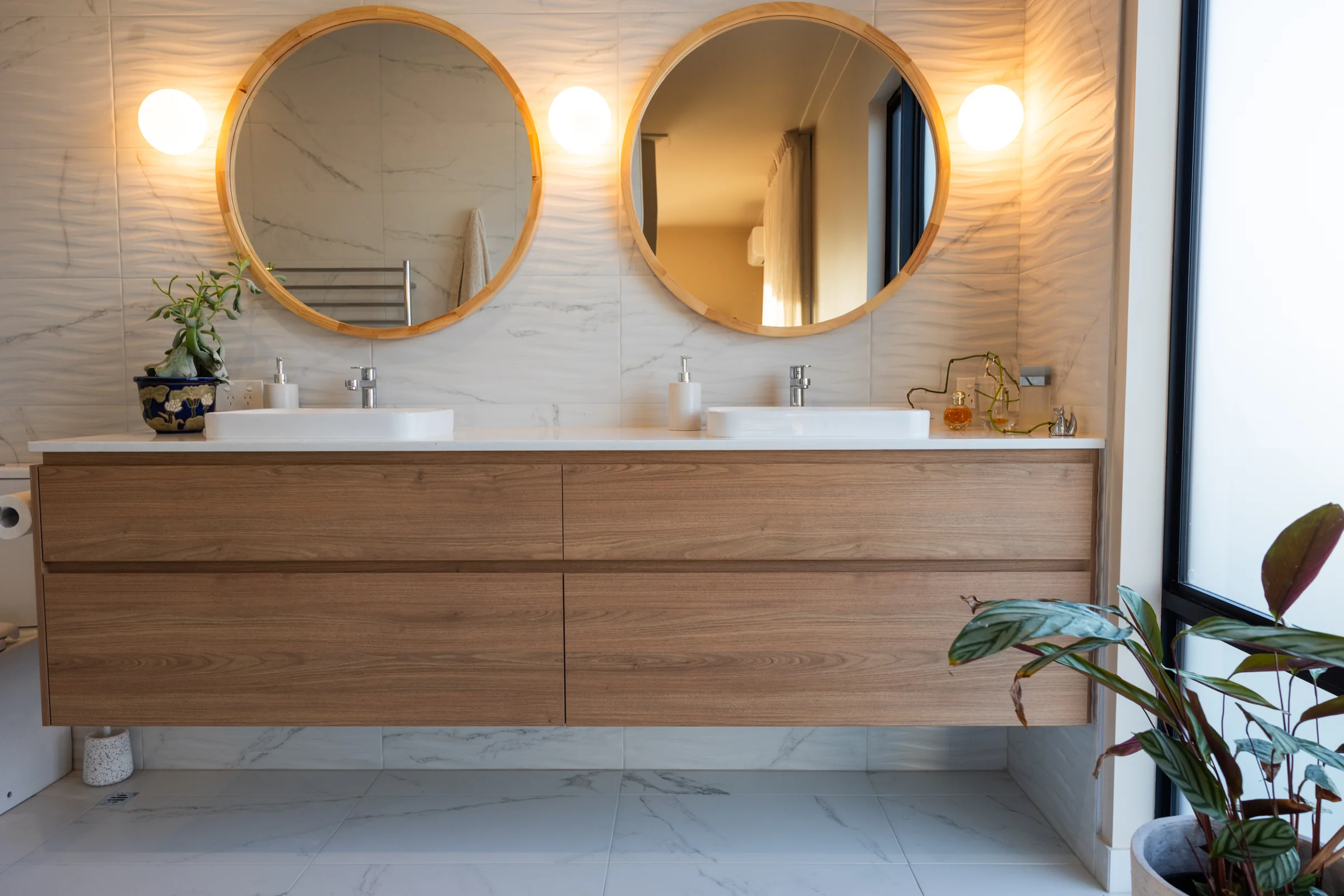 Floating oak-look double vanity under two round mirrors