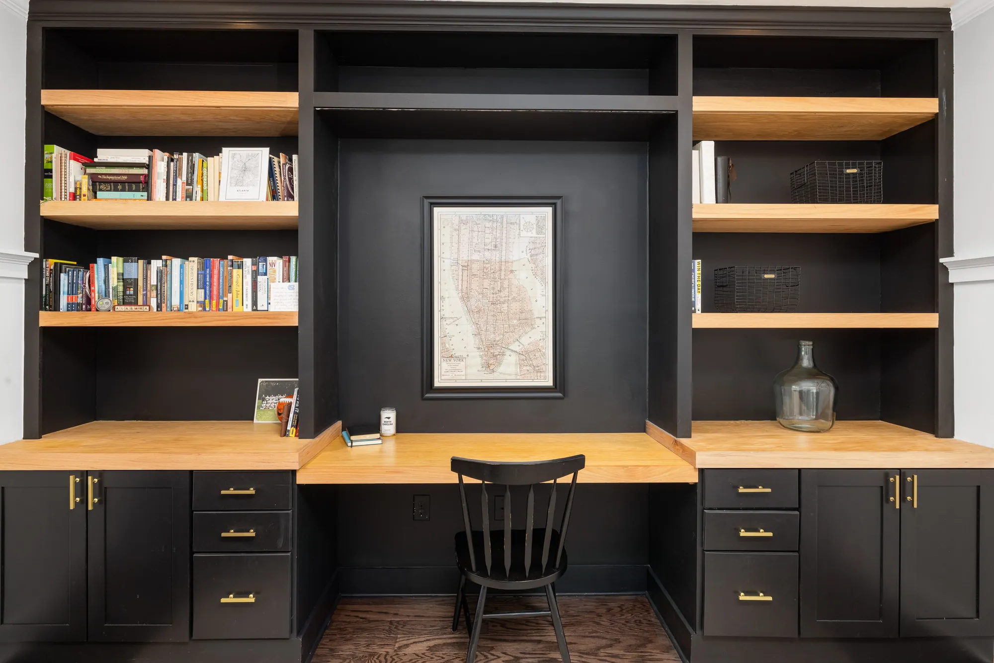 Built-in black shelving with oak shelves and a desk nook