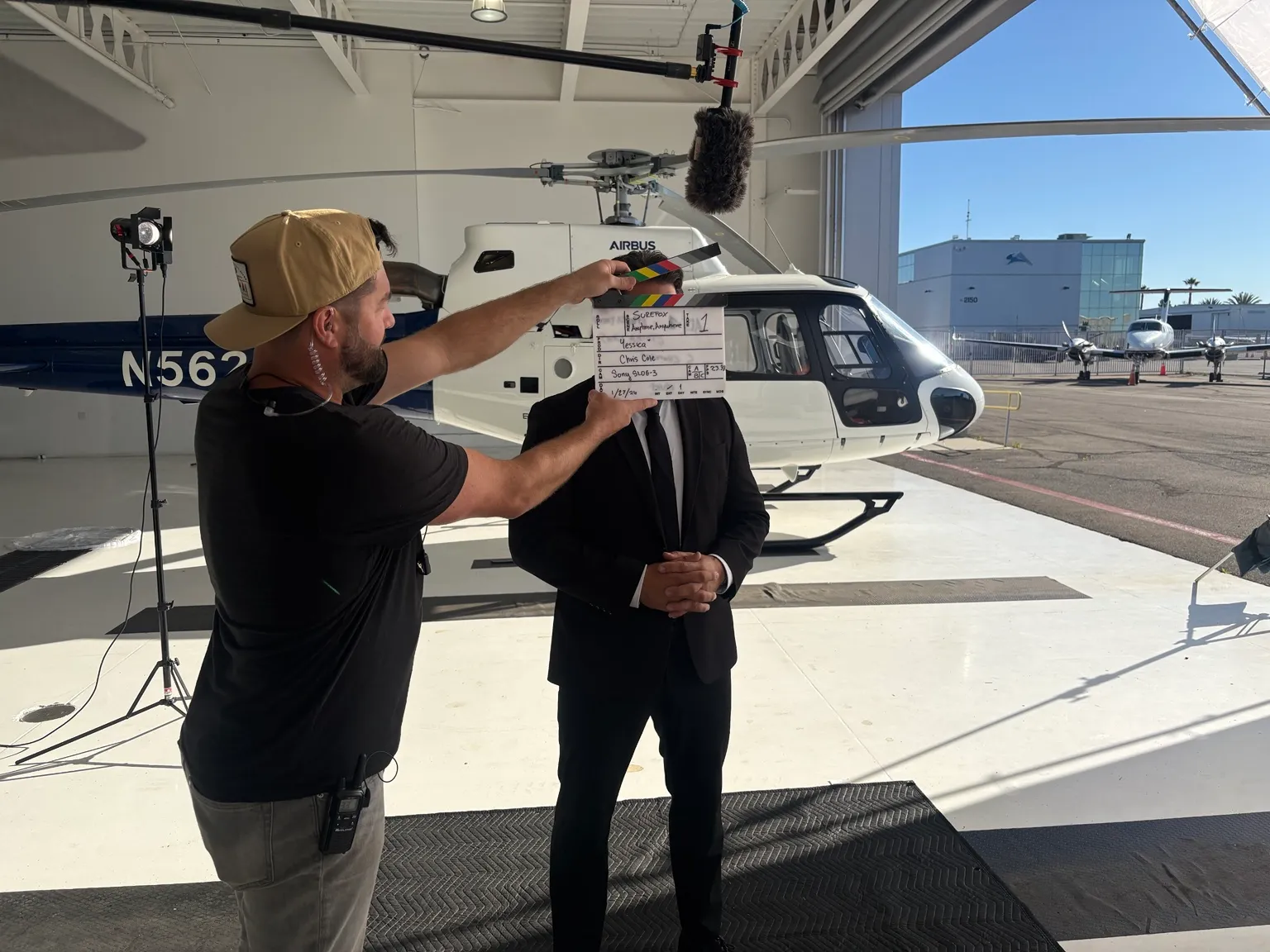Sure Fox behind the scenes with a film slate and helicopter in a hangar