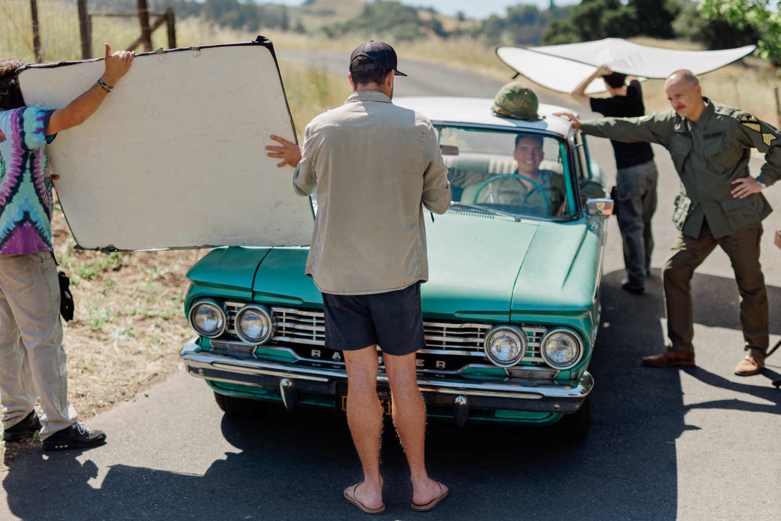 Crew shaping light around a vintage car during a film shoot.