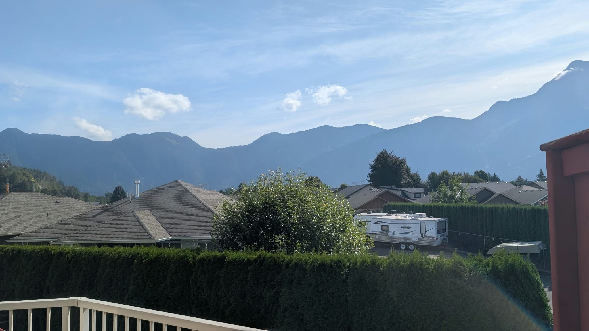 Rooftops and cedar hedges in Agassiz, BC with the mountains behind