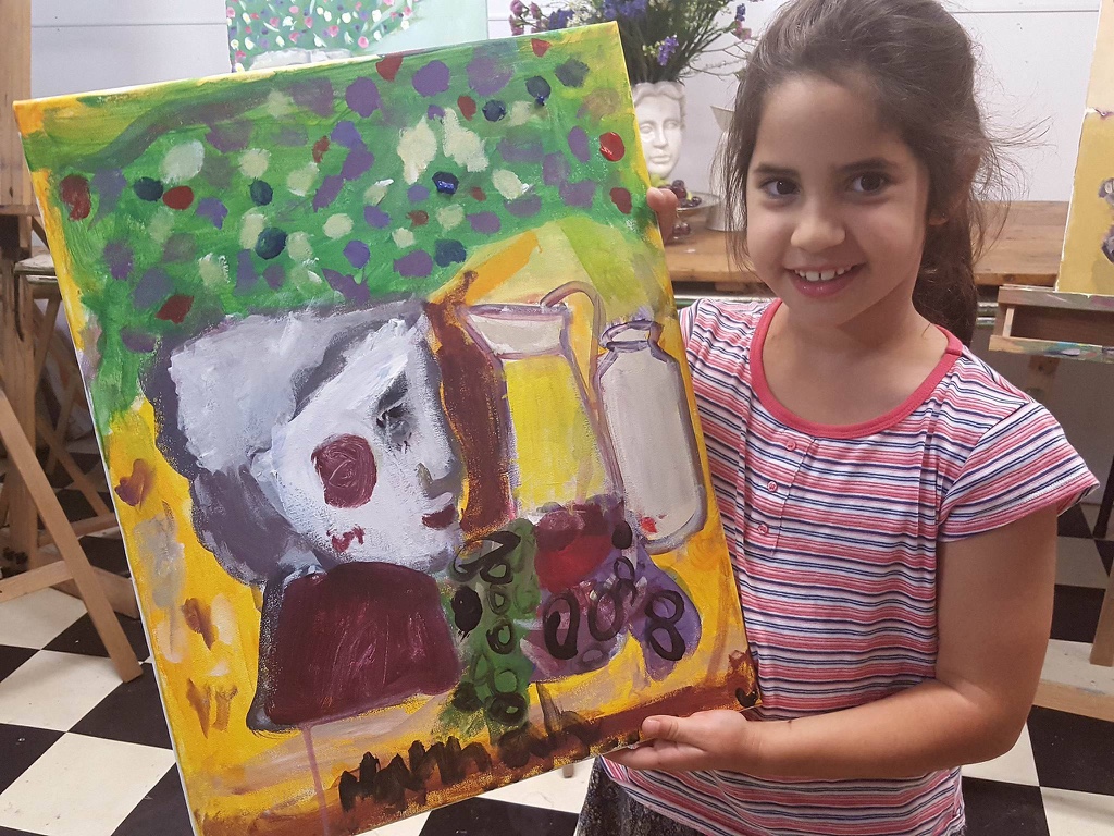 Student holding up a still life painting