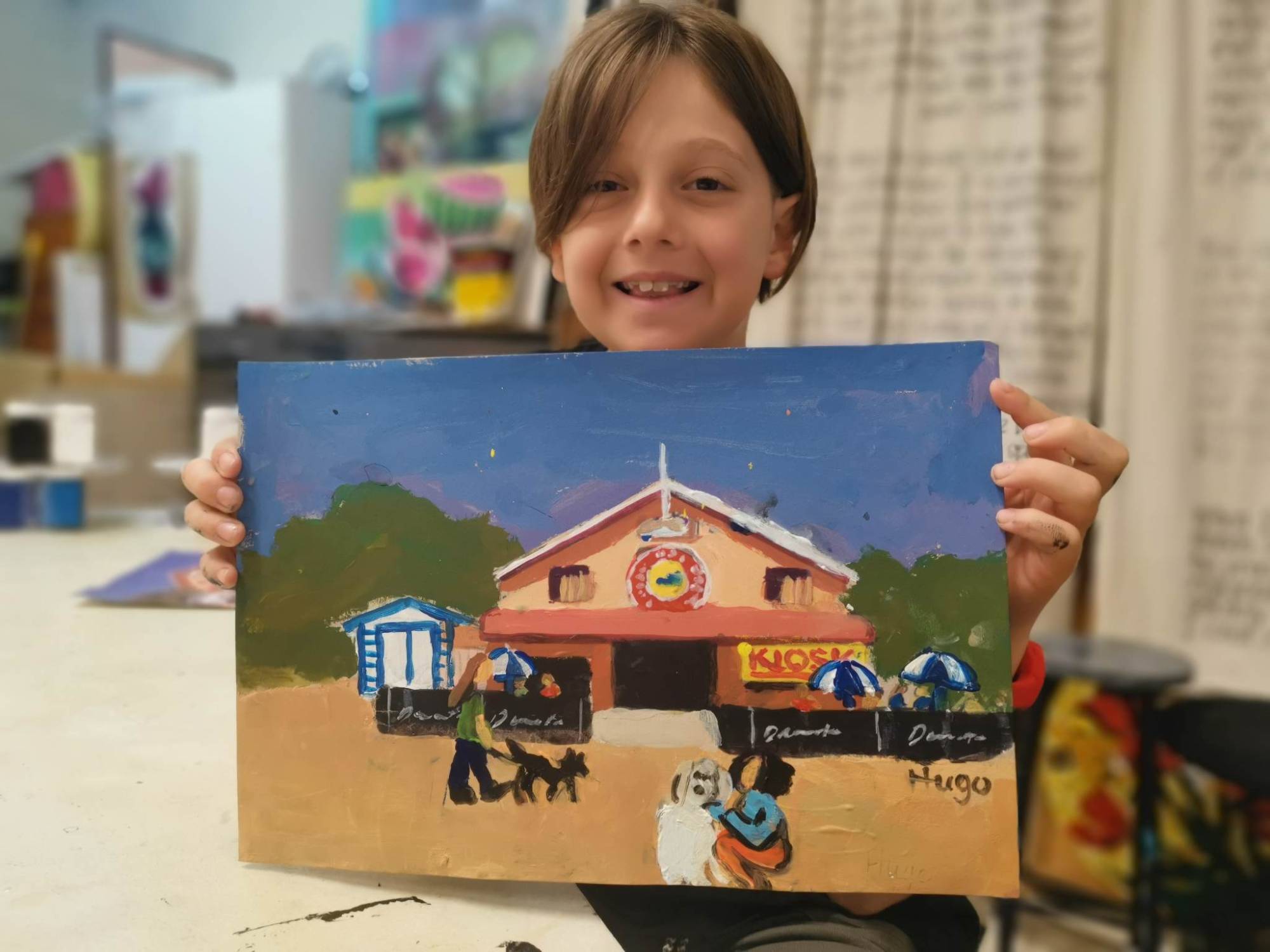 Student holding up a painting of a kiosk