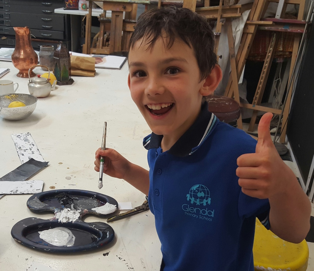 Student giving a thumbs up while painting