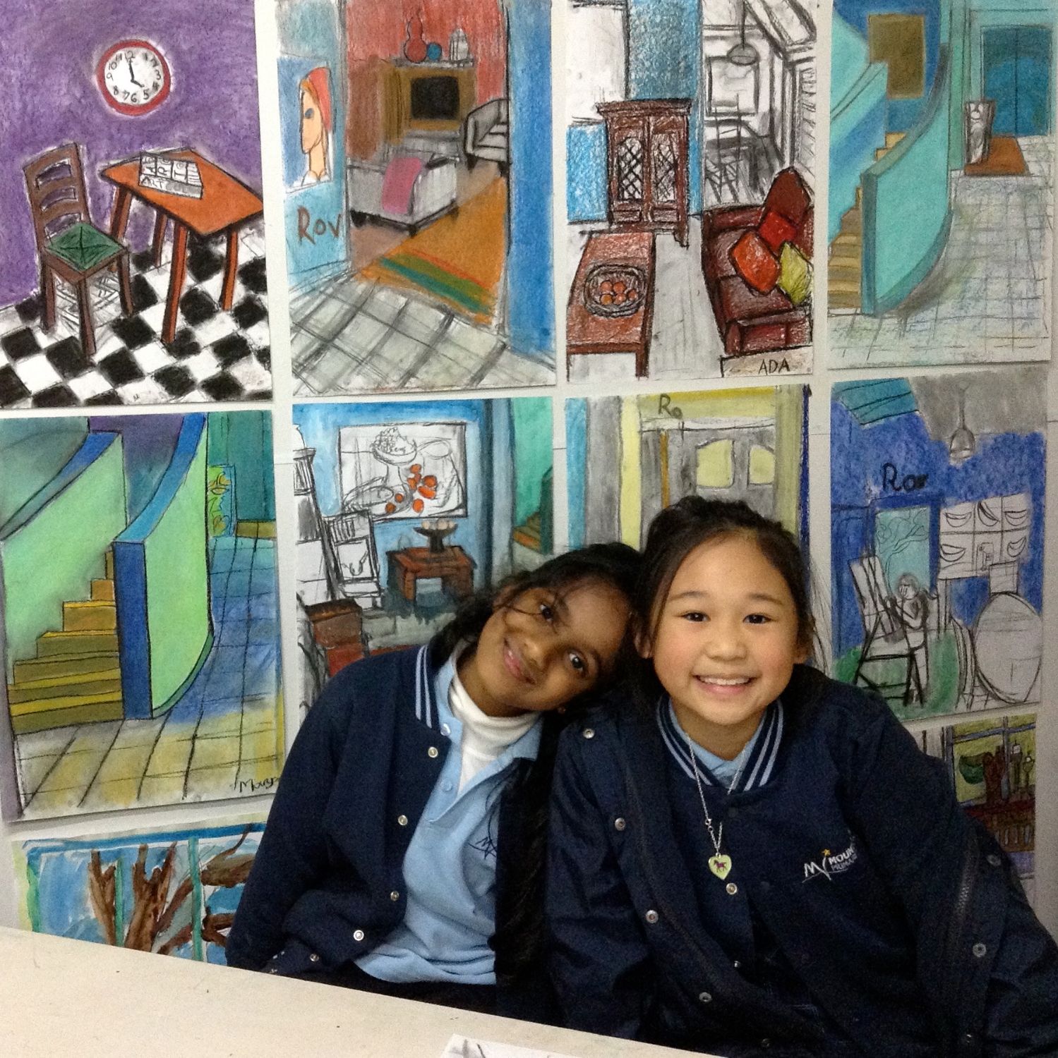 Two students hugging in front of pastel drawings on the wall