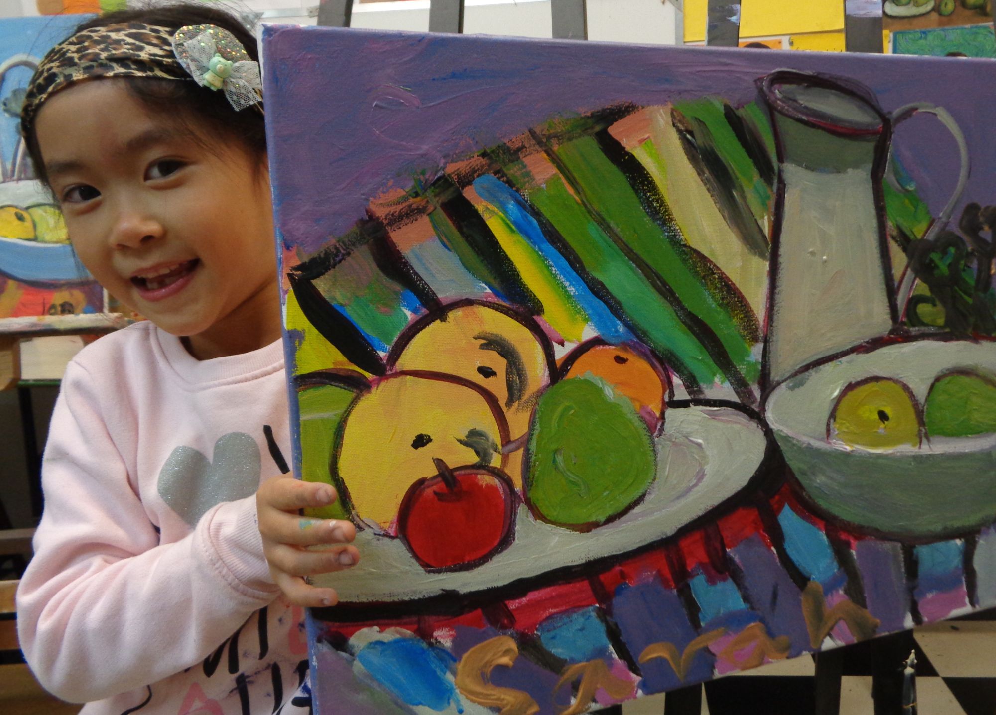 Student holding up her still life fruit painting