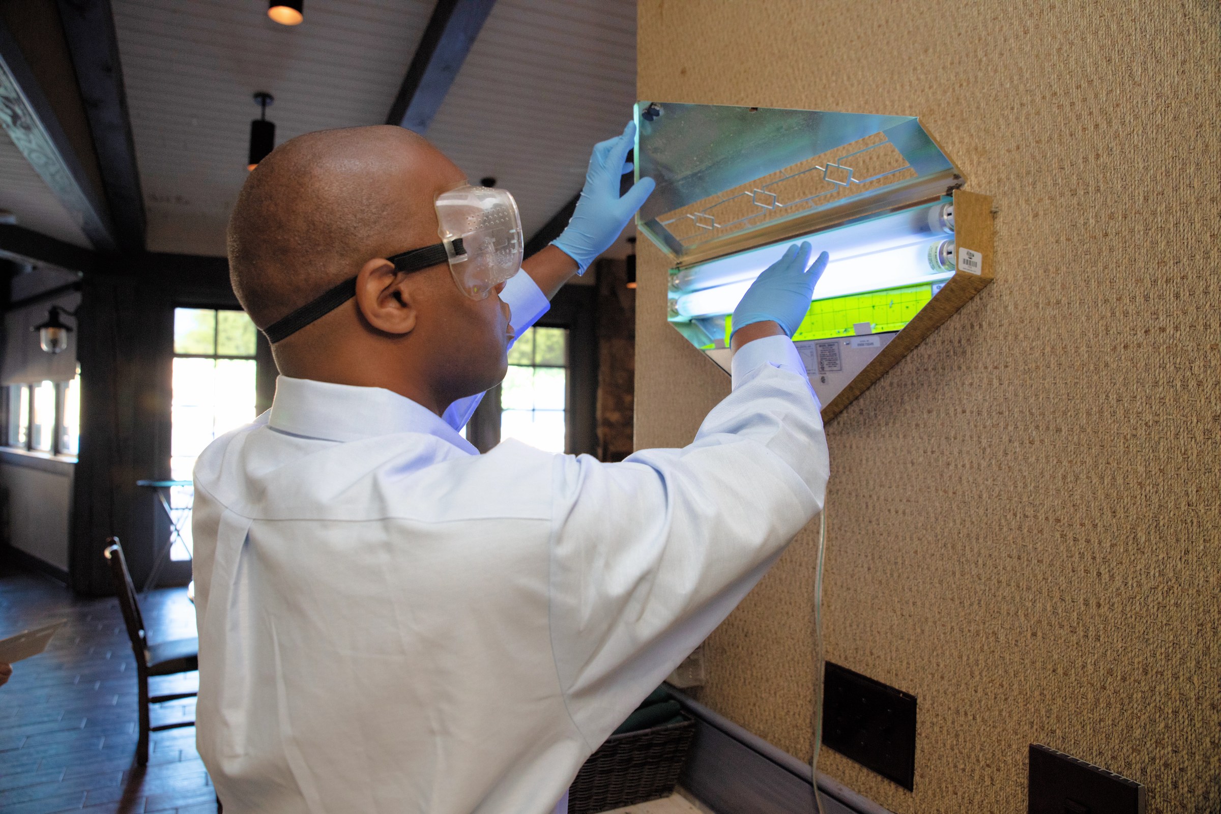 Team Pest USA technician servicing an indoor insect light trap.
