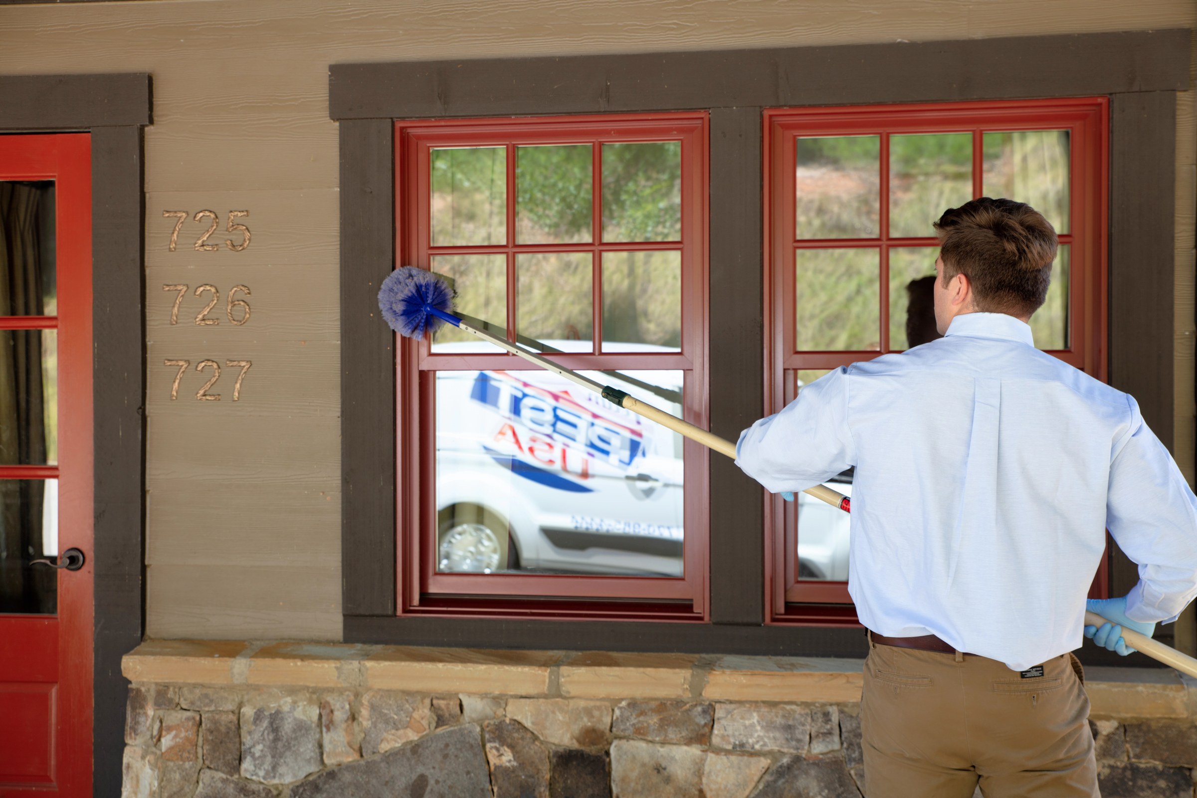 Team Pest USA technician dusting exterior window frames.